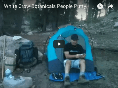 White Crow Botanicals People Putty Video A man sitting in an outdoor tent on the ground.