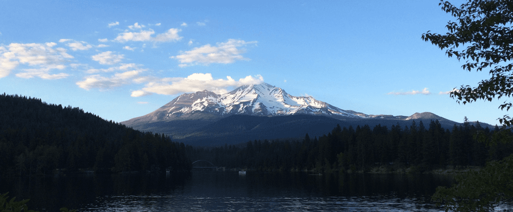 A mountain with snow on top and trees in the foreground.